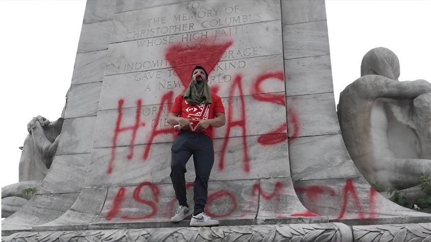 man standing in front of hamas graffiti