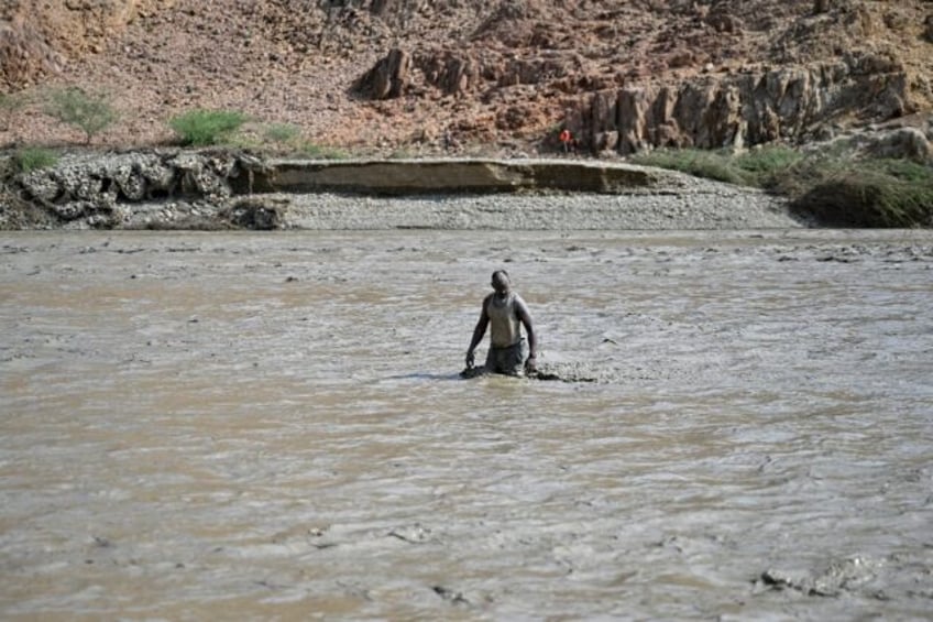 A Sudanese man wades through muddy waters after the collapse of the Arbaat Dam, 40km north