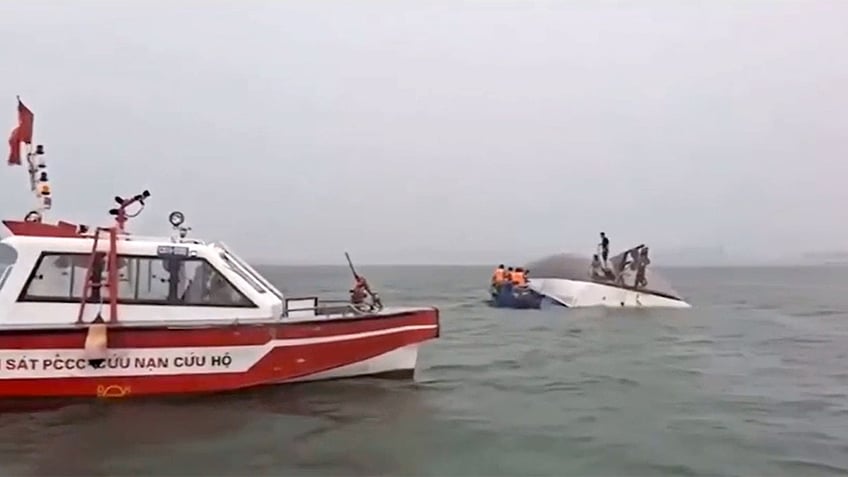 A rescue boat in the foreground of a capsized boat