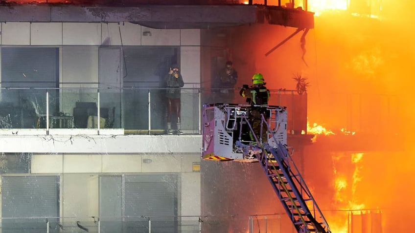 Firefighters on a crane attempt to rescue a resident from a fire