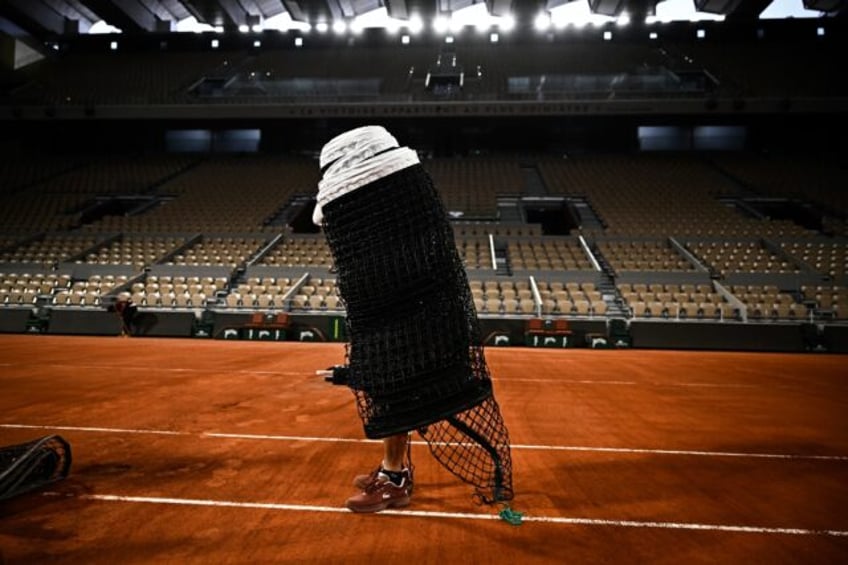 A member of the groundstaff team helps prepare the main Philippe Chatrier court at Roland