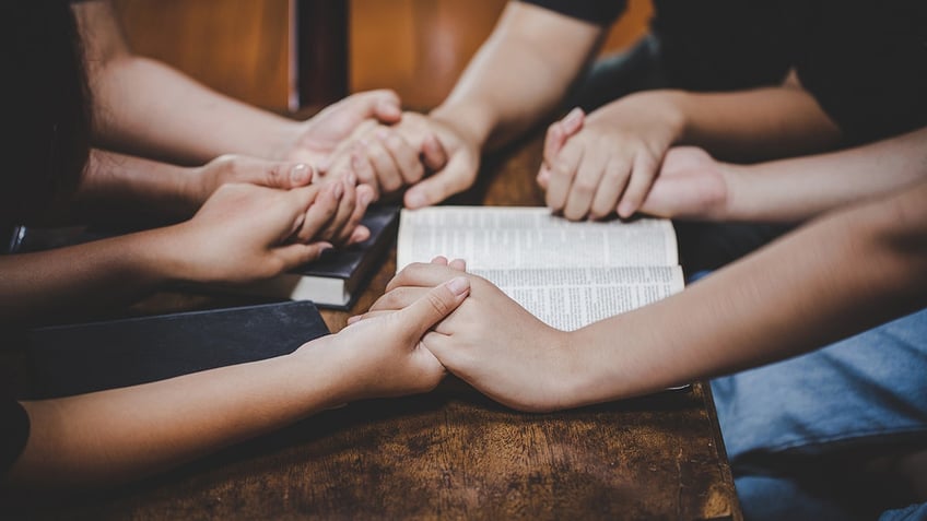 group praying around the table with Bible