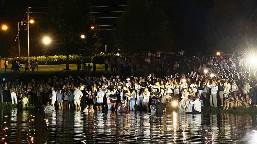 auburn students rush into lake for impromptu baptisms as football coach lends a hand at massive worship event