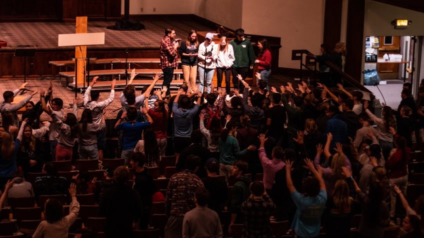 auburn students rush into lake for impromptu baptisms as football coach lends a hand at massive worship event