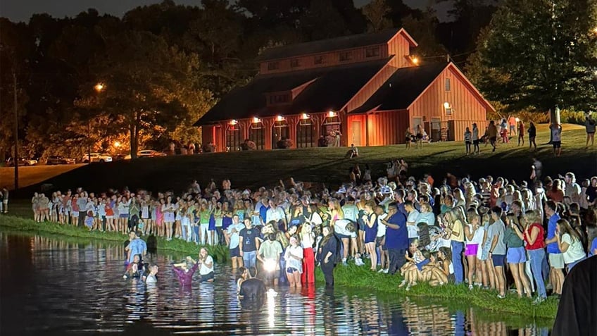 auburn students rush into lake for impromptu baptisms as football coach lends a hand at massive worship event