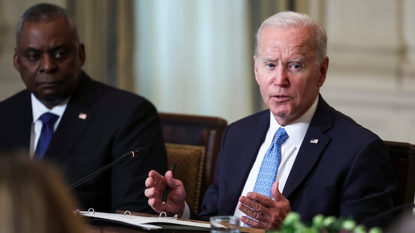 Lloyd Austin, left, listens as President Biden speaks