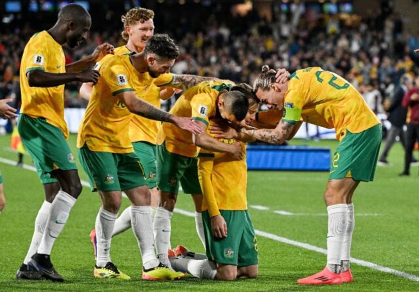 Australia's Craig Goodwin (kneeling) celebrates scoring against China