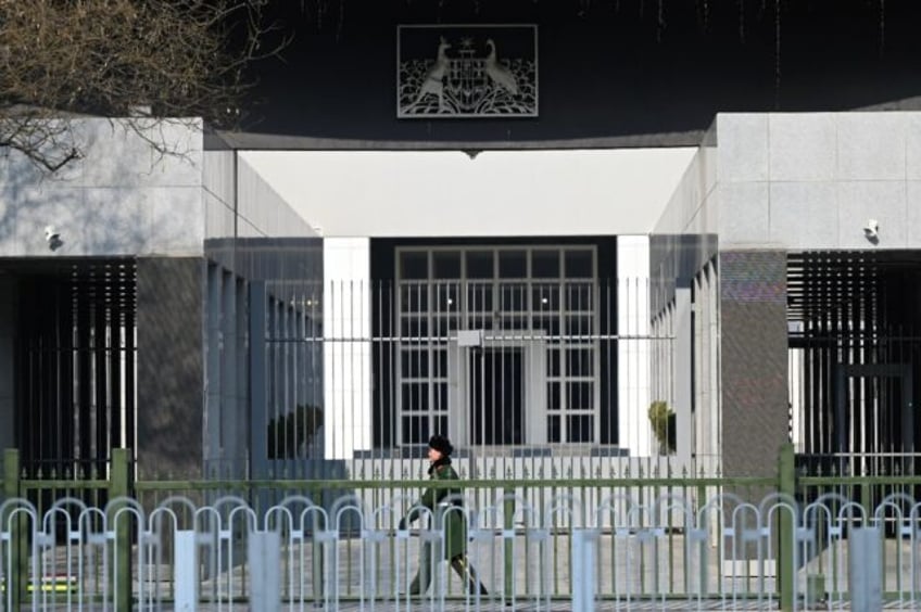 A Chinese paramilitary police officer stands guard outside the Australian embassy. Australia has expressed 'outrage' after writer Yang Jun was handed a suspended death sentence