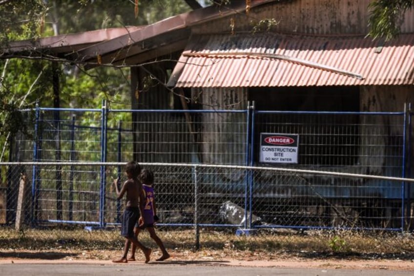 Children walk past a damaged home in Binjari, a remote Indigenous community in Australia's