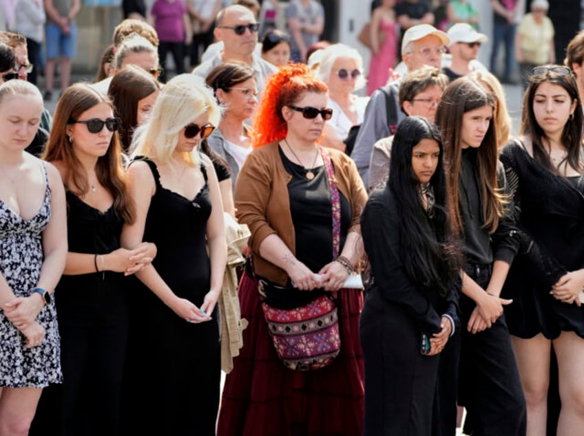 People pay a moment of silence on the main square after a former student opened fire the d