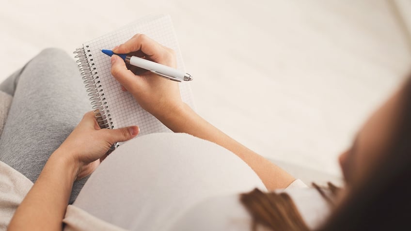 pregnant woman writing baby names