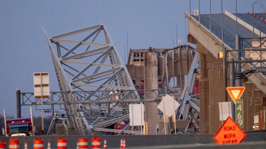 Baltimore bridge collapsed in the background as emergency vehicles are seen in the foreground