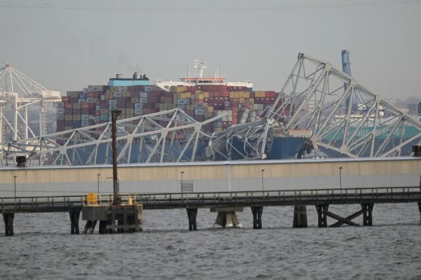 The steel frame of the Francis Scott Key Bridge sits on top of a container ship after the