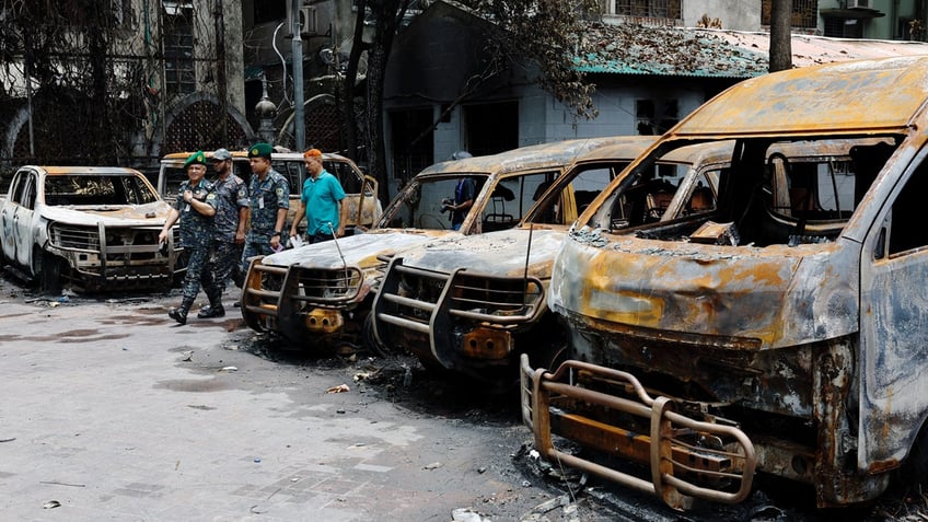 Burned out cars are seen as security officials walk by.