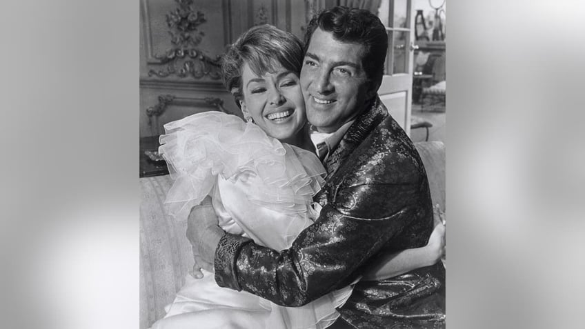 Dean Martin and Barbara Rush hugging and smiling on set.