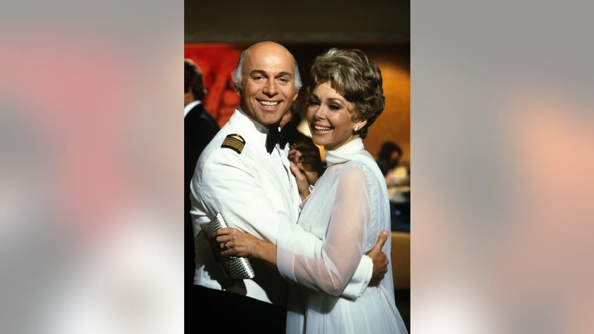 Barbara Rush and Gavin MacLeod dancing together on set of a film.