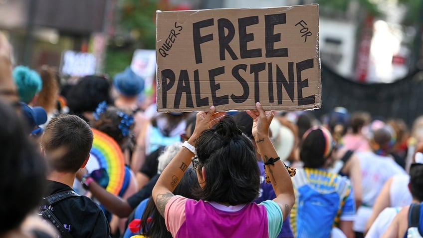 Person holds up a "Queers for a Free Palestine" sign