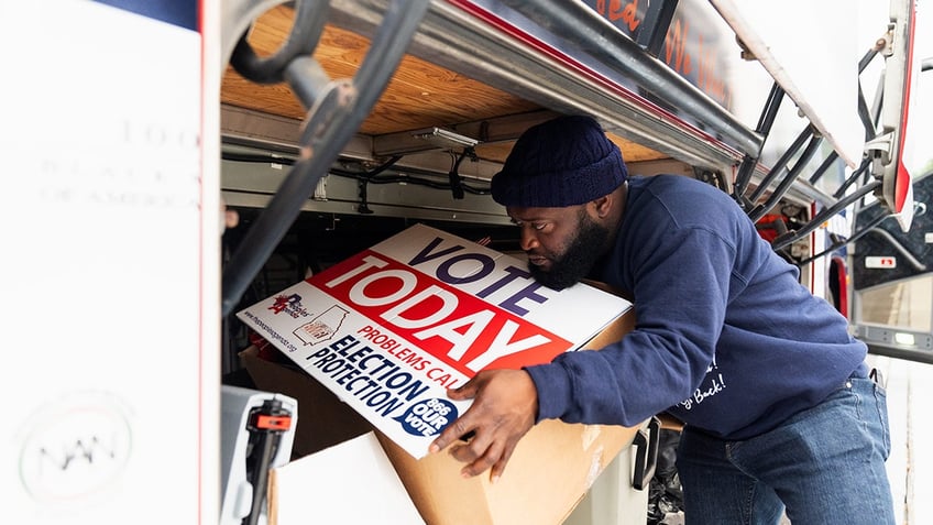 Sean Floyd of the National Coalition on Black Civic Participation helps load signs onto a bus before he and other canvassers head to Clayton County to canvass