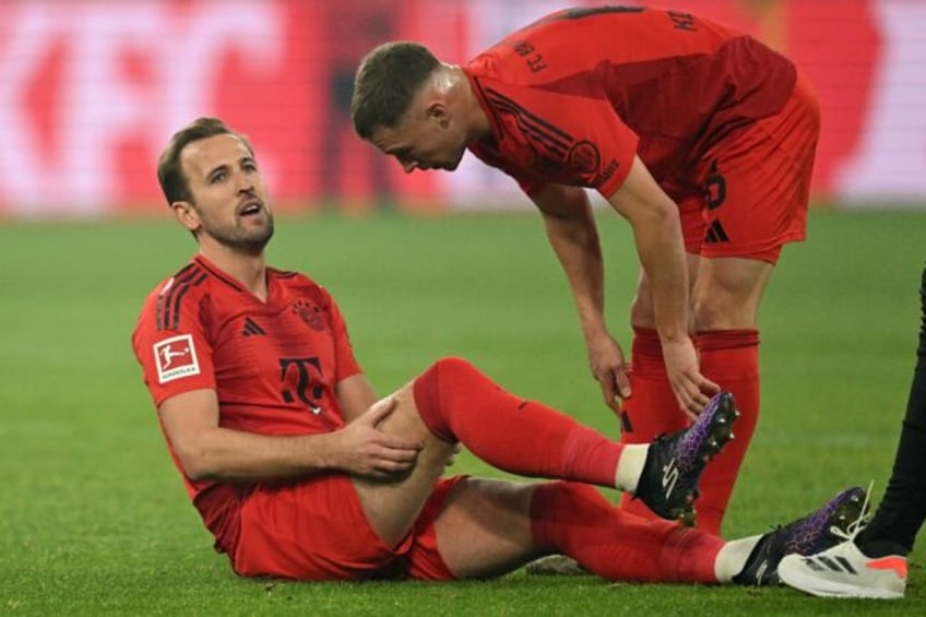 Bayern Munich forward Harry Kane (L) grabs his injured hamstring before being subbed off i