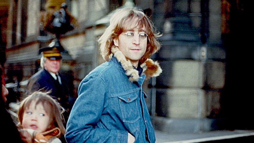 John Lennon wearing a denim jacket outside.