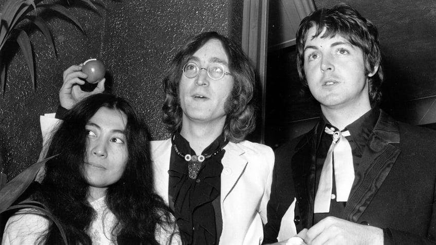 Yoko Ono, John Lennon and Paul McCartney standing together and looking serious