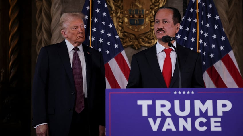 Trump at left as businessman speaks at press conference