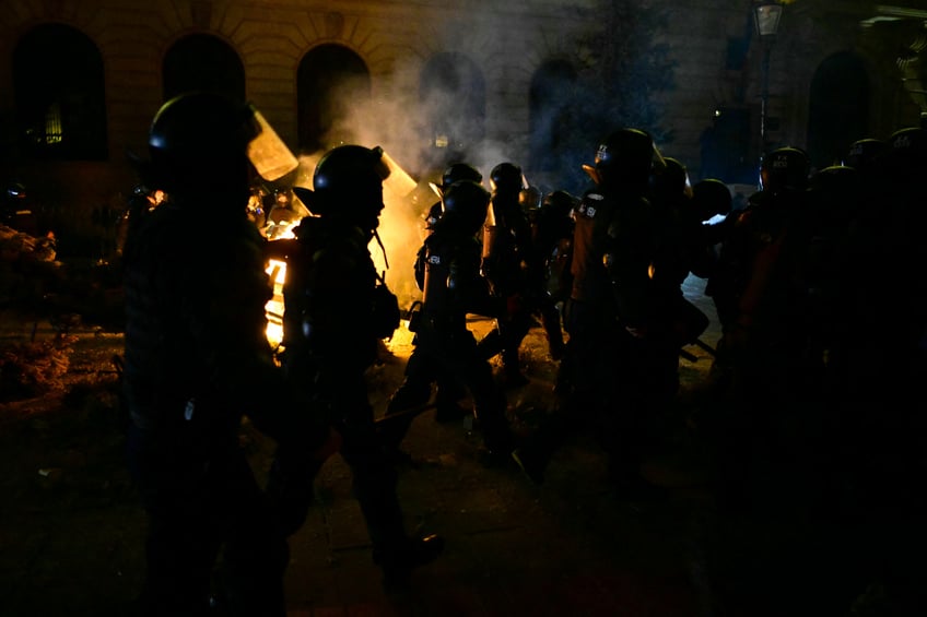 Romanian gendarmes in riot gear walk past a fire as they face protesters amid clashes during a demonstration near the Central Electoral Bureau in Bucharest on March 9, 2025, after the electoral bureau rejected Georgescu's candidacy for the re-run of last year's annulled presidential election. Georgescu, a past admirer of Russian President Putin and an EU and NATO critic, shot to prominence almost overnight to unexpectedly win the first round of a presidential election last November. But in a shock move Romania's constitutional court annulled the ballot shortly before the second round was to be held in December, after claims of Russian meddling and a "massive" social media promotion of Georgescu. In a statement on March 9, the electoral bureau said it had adopted "the rejection of the registration of the independent candidacy" of Georgescu for May's re-run, without giving its reasons for doing so. Georgescu, who is currently leading opinion polls with about 40 percent of the vote, can challenge the decision at Romania's constitutional court. (Photo by Daniel MIHAILESCU / AFP) (Photo by DANIEL MIHAILESCU/AFP via Getty Images)