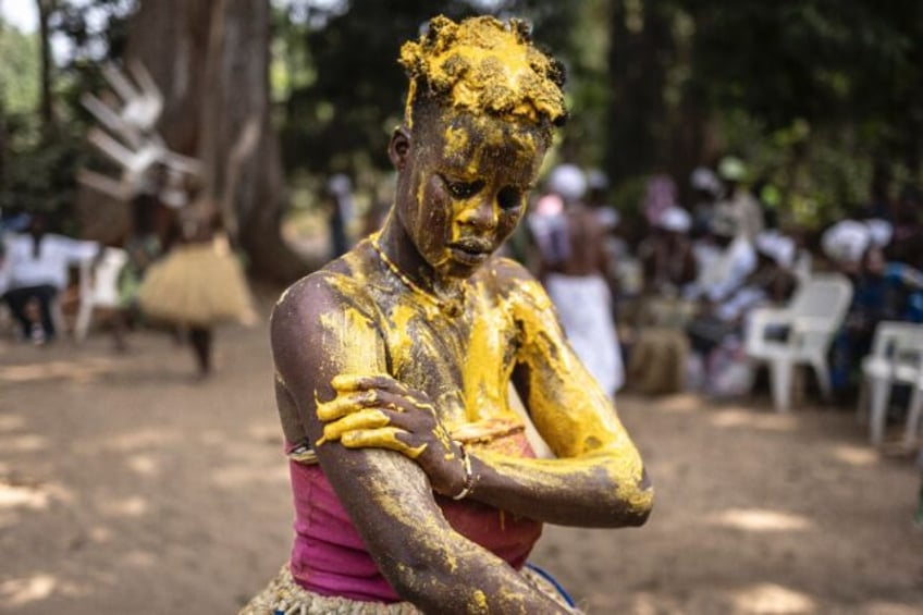 An initiate Kokou, a traditional warrior deity, covers herself with a mixture of red veget