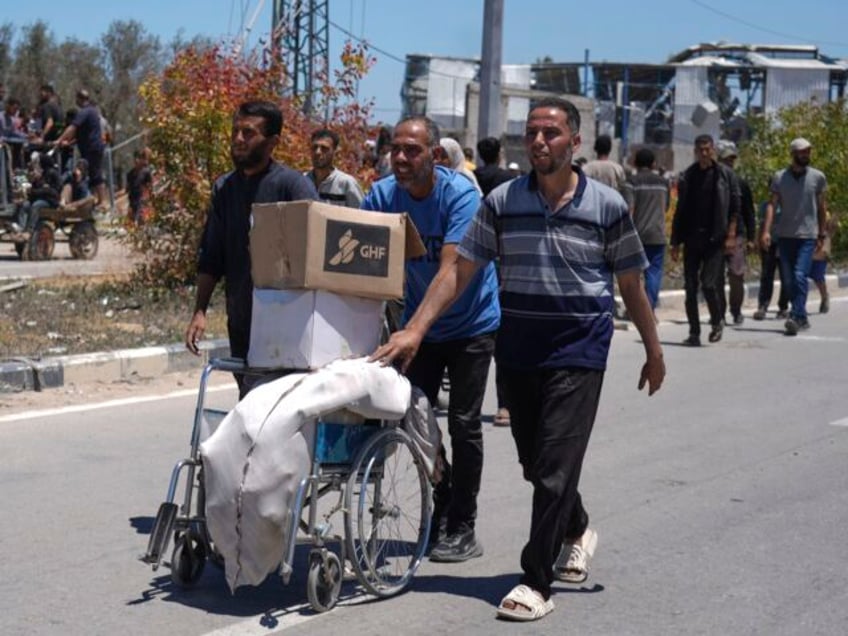Palestinians carry boxes and bags containing food and humanitarian aid packages delivered