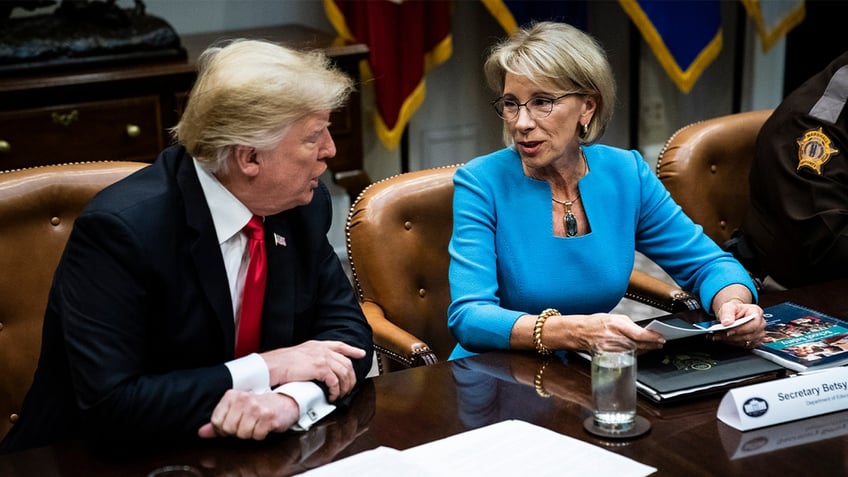 Donald Trump speaks with Betsy DeVos at a roundtable with family members of victims, state and local officials, and Cabinet members to discuss recommendations in the Federal Commission on School Safety Report in the Roosevelt Room at White House on, Dec. 18, 2018 in Washington, D.C. (Photo by Jabin Botsford/The Washington Post via Getty Images)