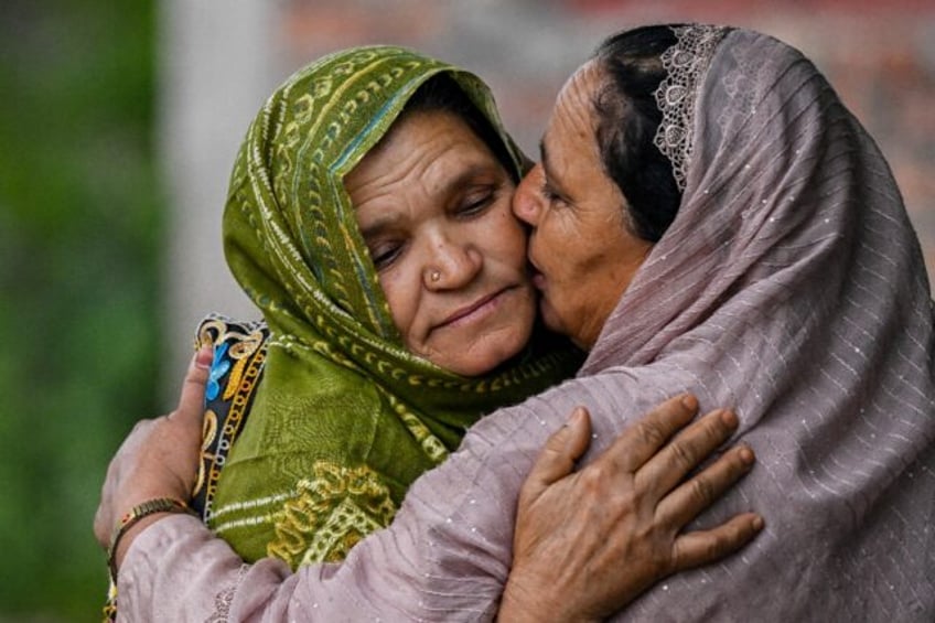 Nasreen Akhtar Bi (L) is embraced by her relative at her home in Salwah village near Mendh