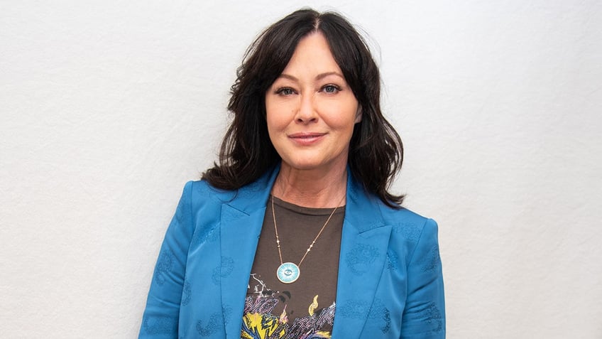 Shannen Doherty smiling in a blue blazer and graphic t-shirt