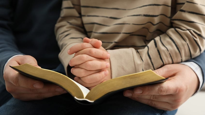 Boy and his parent reading Bible together,