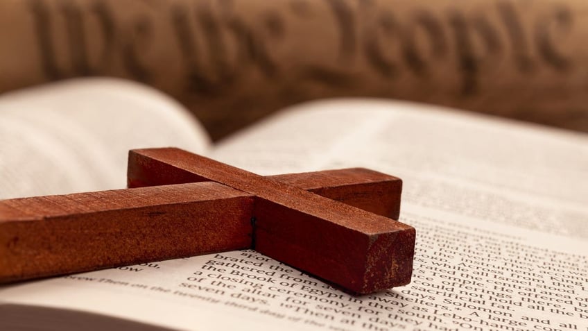 Close up of a religious cross atop the pages of a Bible