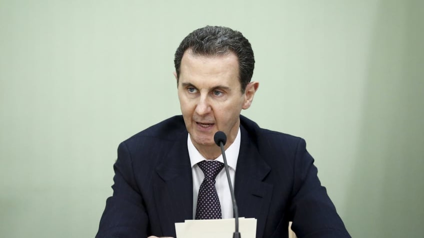 Bashar al-Assad reading prepared remarks into microphone