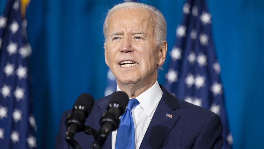 President Biden at microphone with US flags behind him