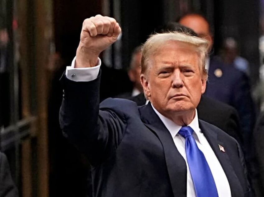 Former US President and Republican presidential candidate Donald Trump holds up a fist as