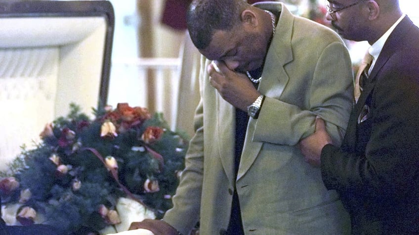 Oswald Clarke wipes tears from his eyes alongside his sister Karen's casket after her murder