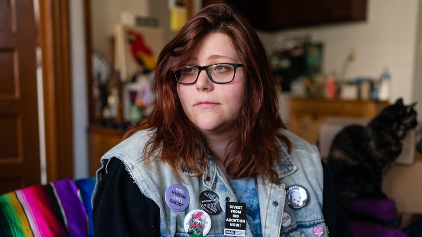 pro-life activist shown seated, wearing jean vest