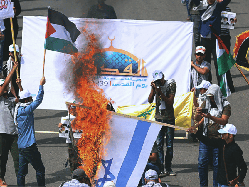 Iraqi Popular Mobilization Forces burn a representation of Israeli flag as they hold a Pal