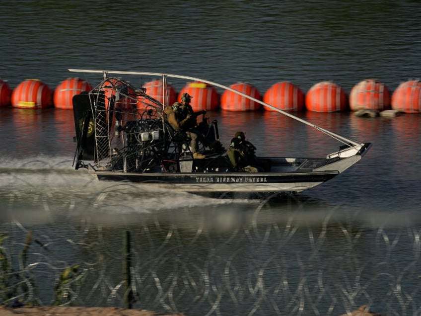 A Texas Highway Patrol boat passes a chain of buoys deployed to help curb illegal crossing