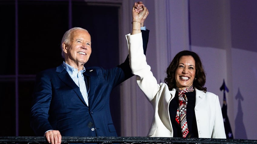 President Joe Biden and VP Kamala Harris with arms raised on Truman Balcony 