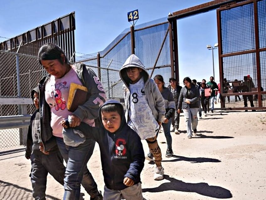 Migrants with children walk to board a bus after surrendering to US Customs and Border Pro