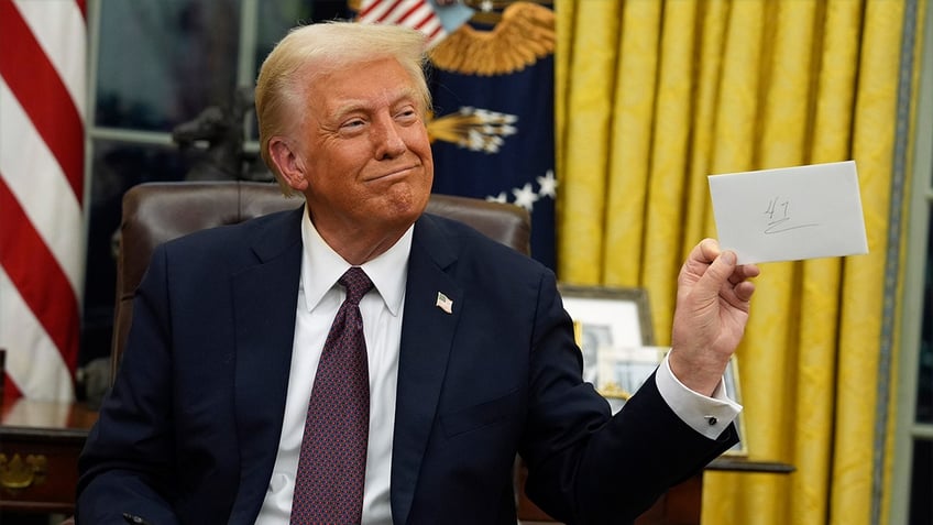 President Donald Trump holds up letter