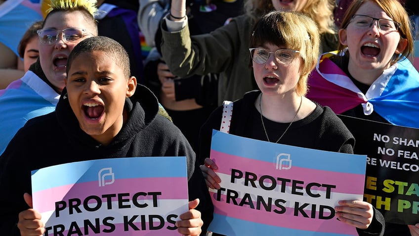People protesting with "protect trans kids" signs