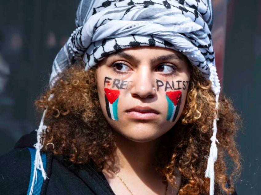 A Palestinian supporter stands with others near at the Israeli Consulate where supporters