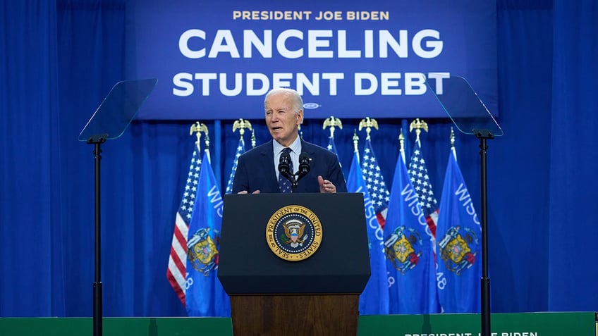 Biden stands over canceling student debt sign