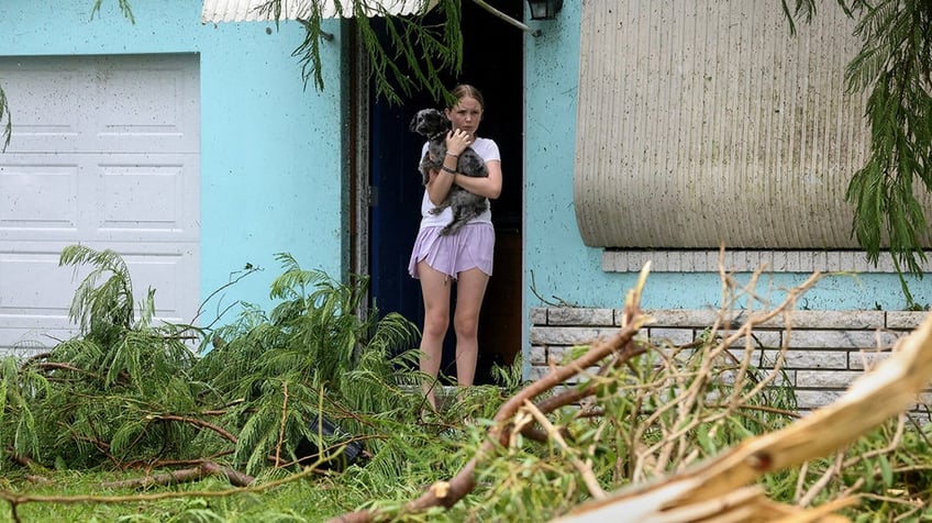 Mallory Tollett comforts her dog Maggie after a suspected tornado went through her family's property along Southeast Azimuth Way as Hurricane Milton bands move through Port Salerno