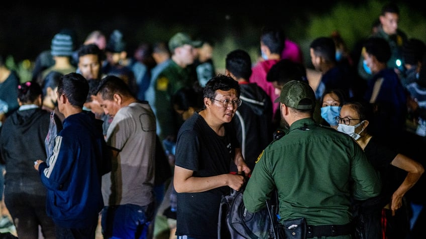 Chinese migrants speak to a border patrol officer before being processed