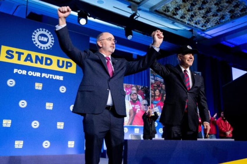 US President Joe Biden and Shawn Fain, President of the United Auto Workers (UAW), wave during the United Auto Workers union conference